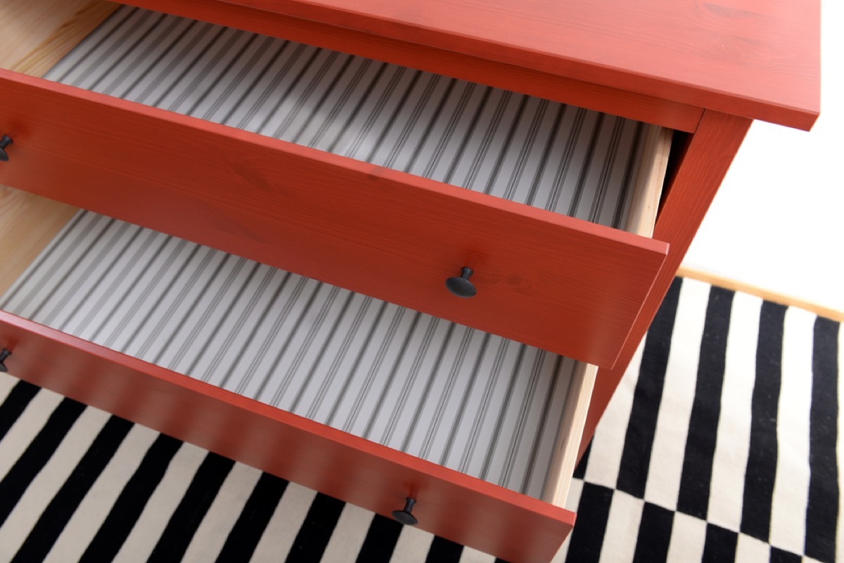 red dresser with empty drawers on a black and white rug