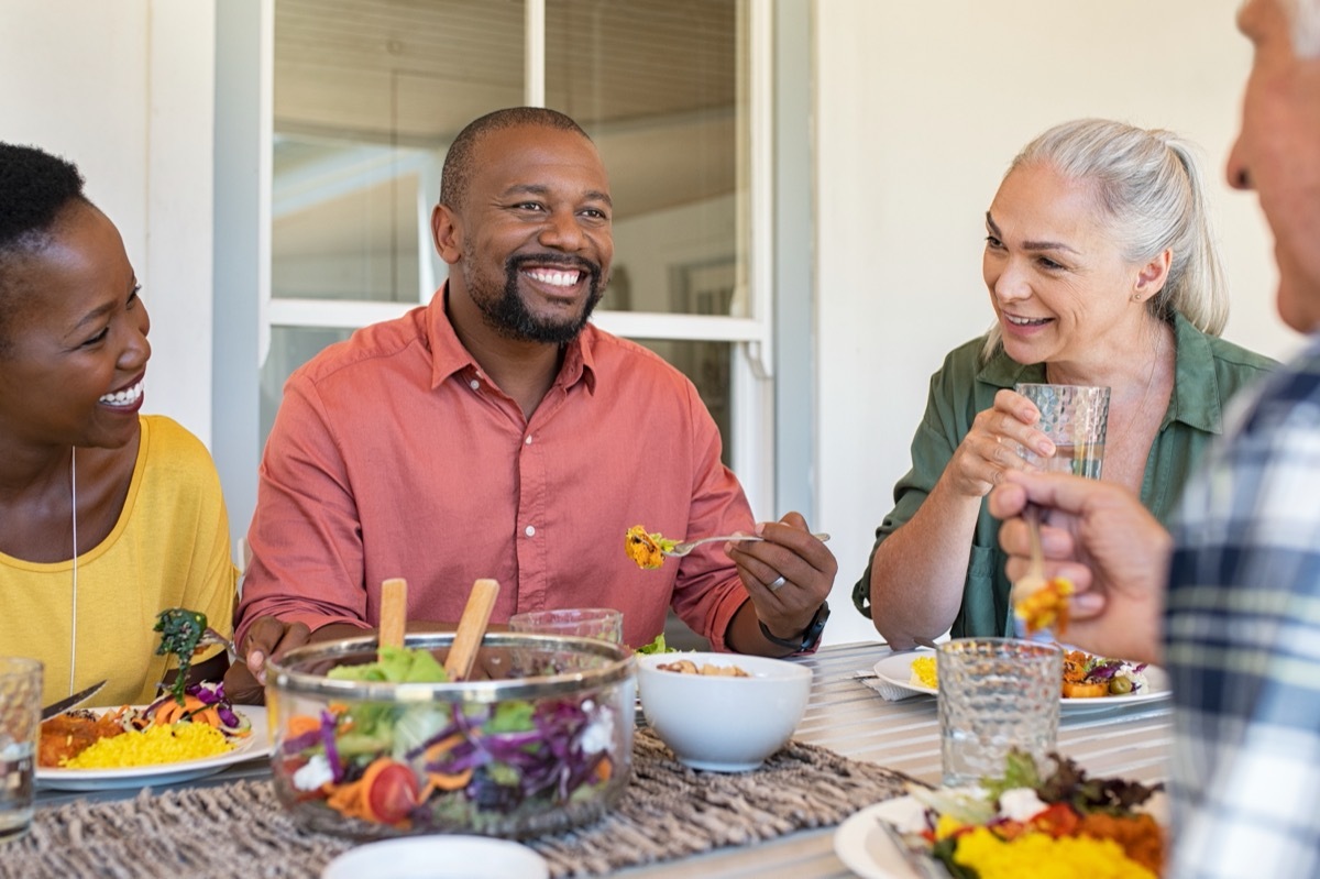 group of middle-aged friends eating together outdoors