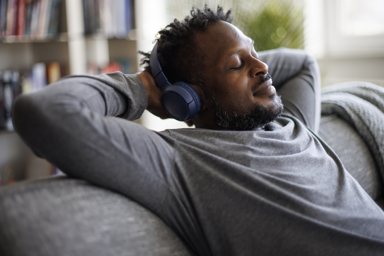 Young man enjoying music over headphones while relaxing on the sofa at home