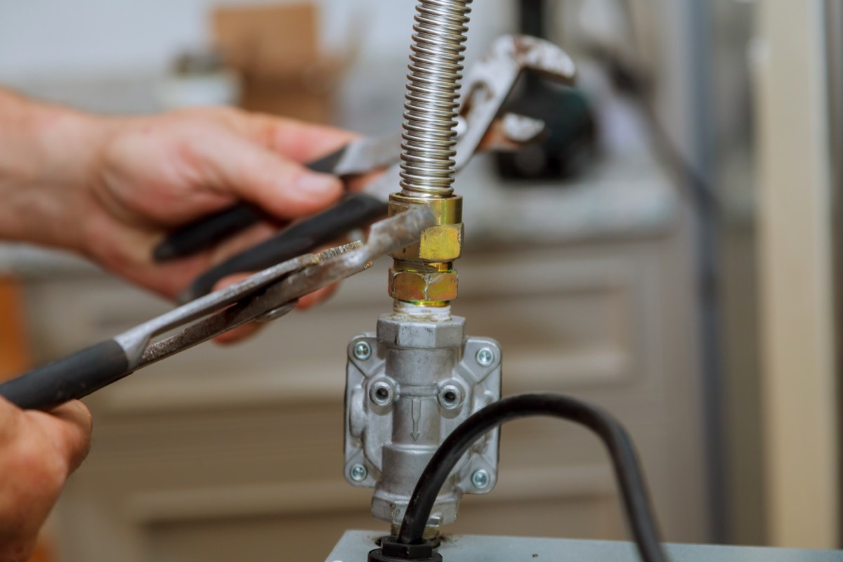 white hand using wrench to tighten nut on gas line