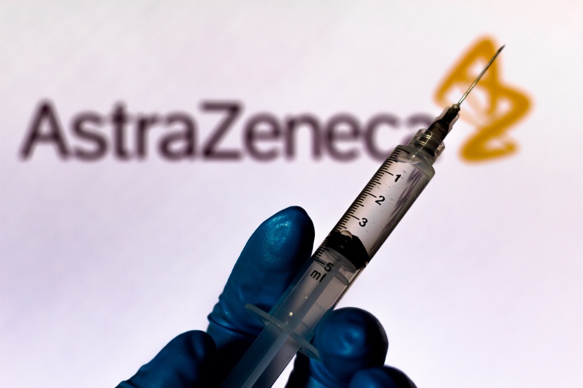 blue glove, holding syringe, astrazeneca sign