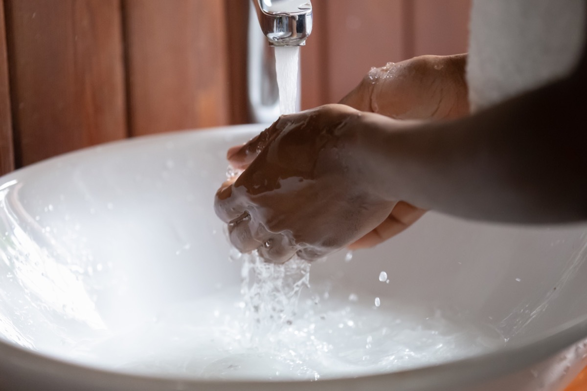 Black person washing their hands in a sink