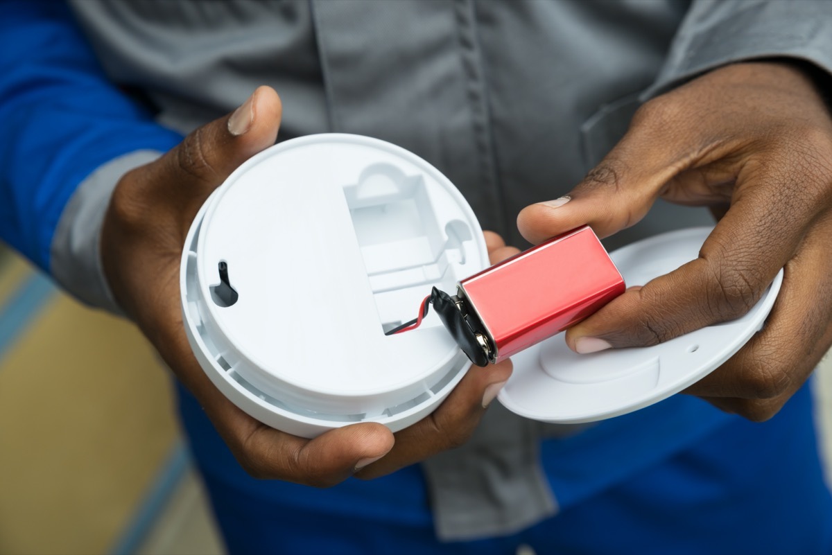 Close-up Of Electrician Hands Removing Battery From Smoke Detector