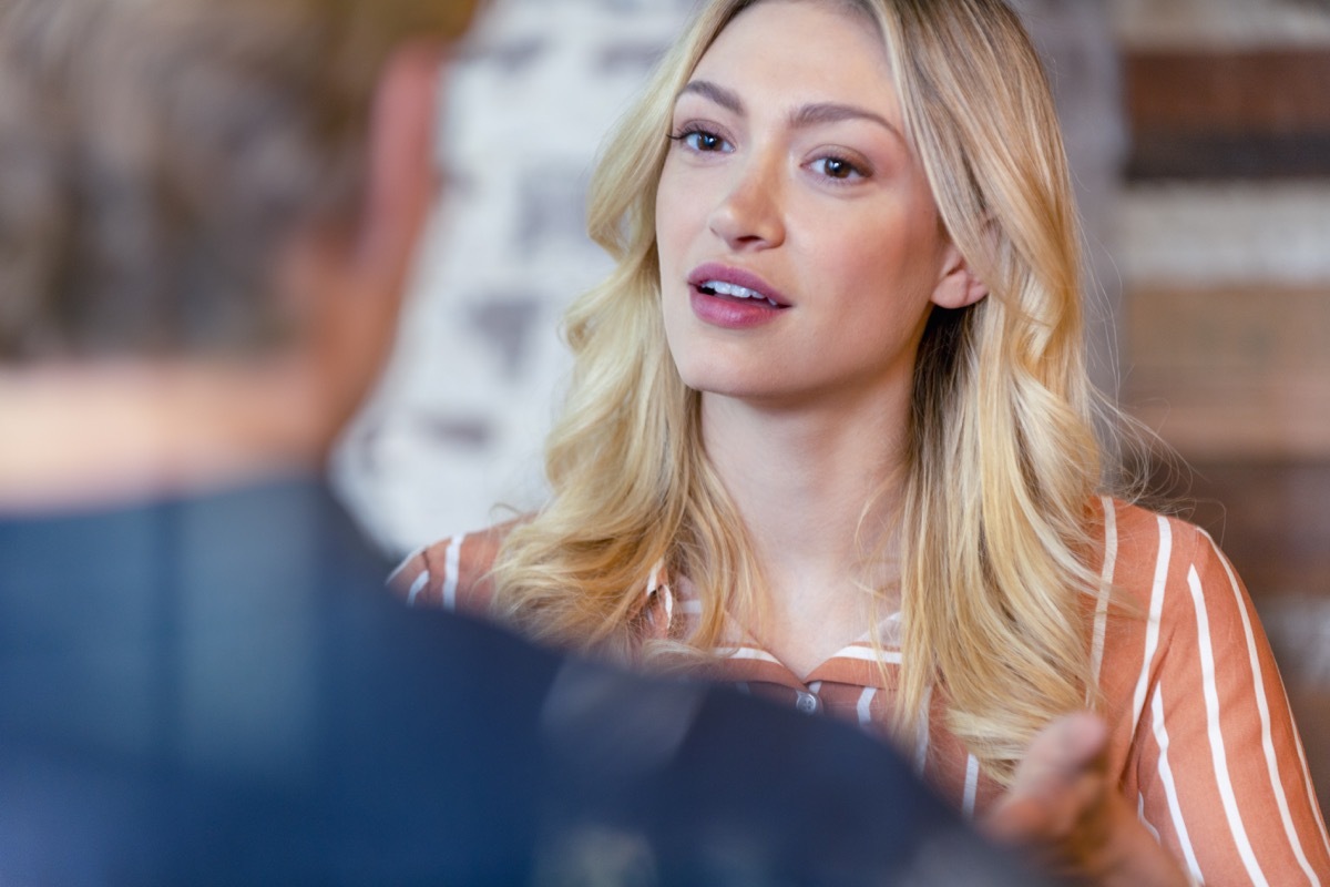 Business man and woman having a conversation. They are both young business people casually dressed. She is talking or listening. Could be an interview or consultant working with a client. She is listening and smiling. One person has his back to us.