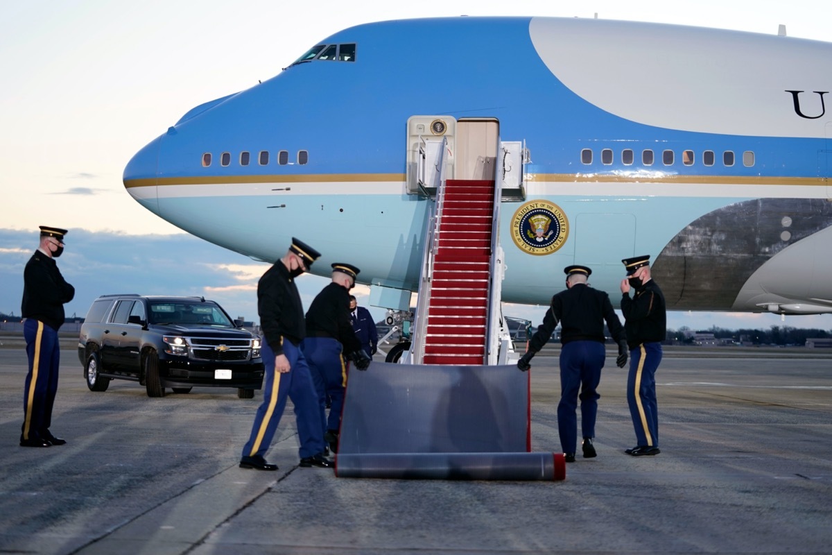 military members roll out a carpet in front of air force one