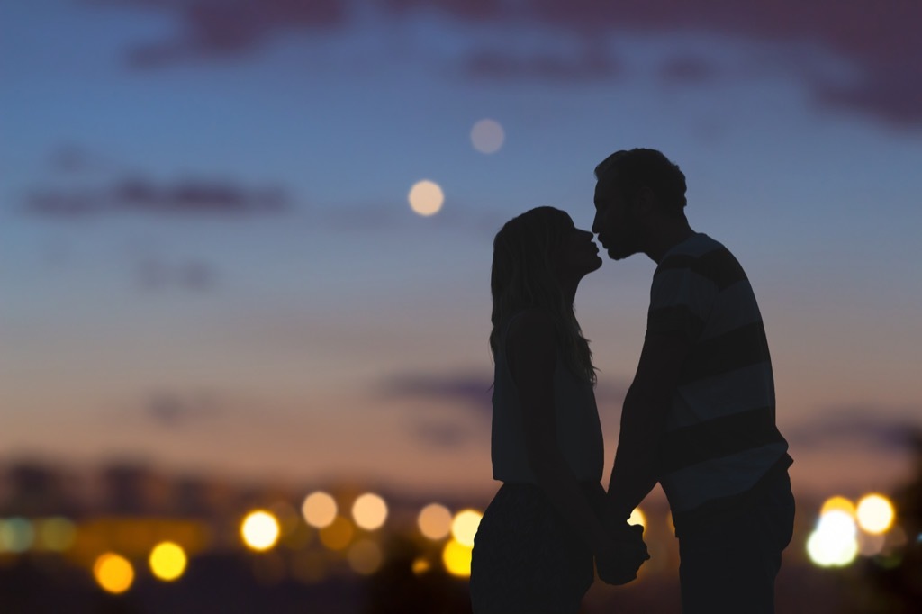 silhouette of couple kissing on a rooftop at dusk