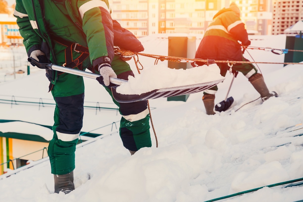 People shoveling snow of roof