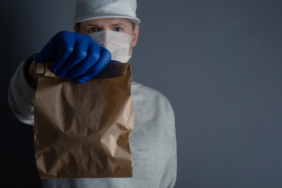 man holds a brown lunch bag