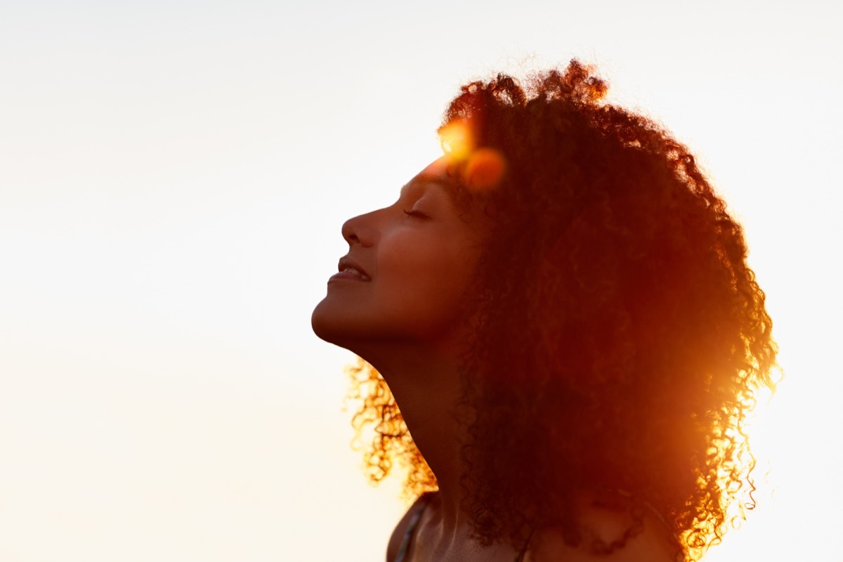 Woman smilling during a sunset taking in nature sounds