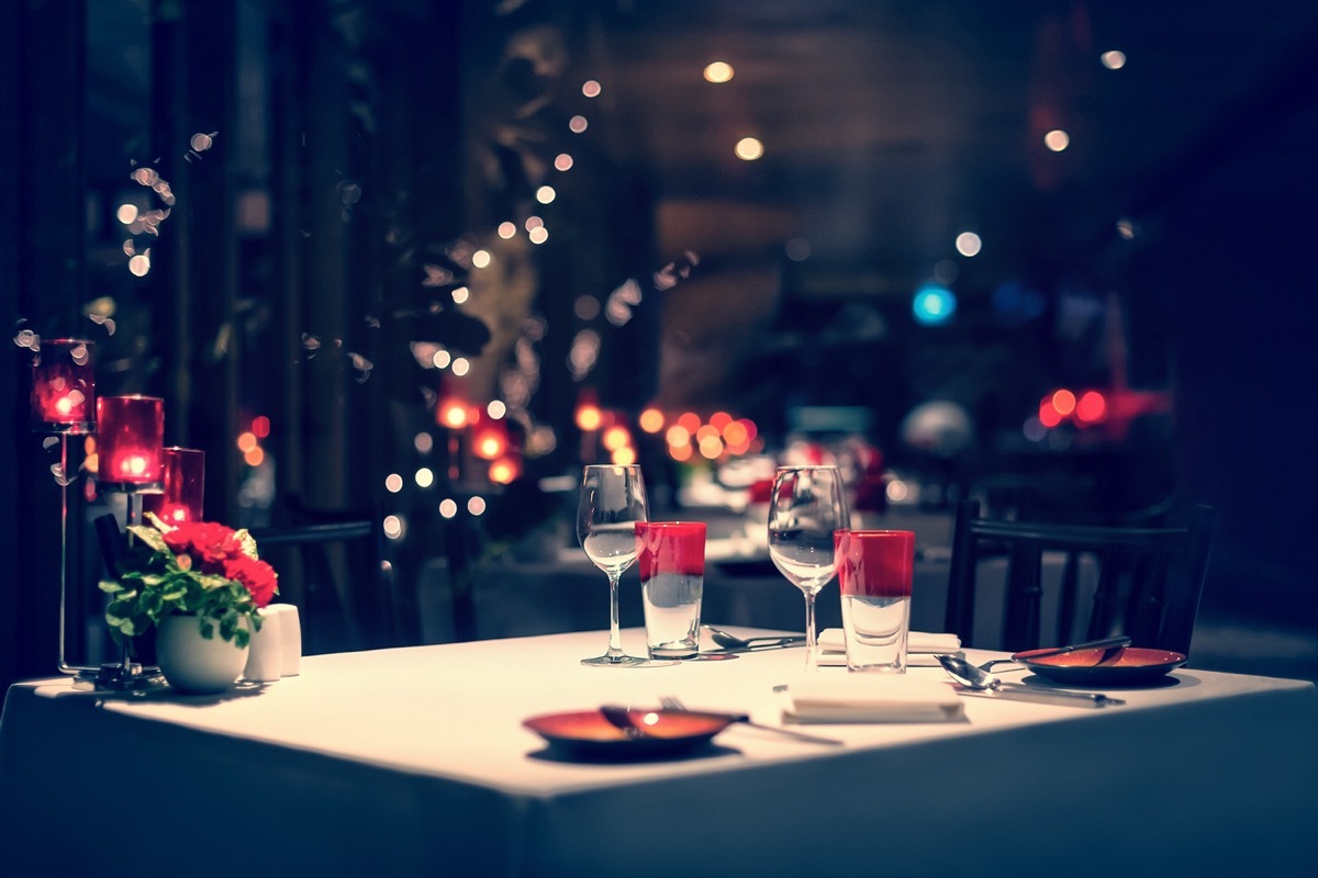 A fancy dinner set up with red decorations and a candle