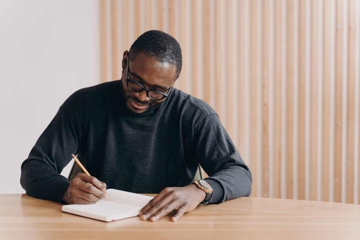 focused young man writing in journal