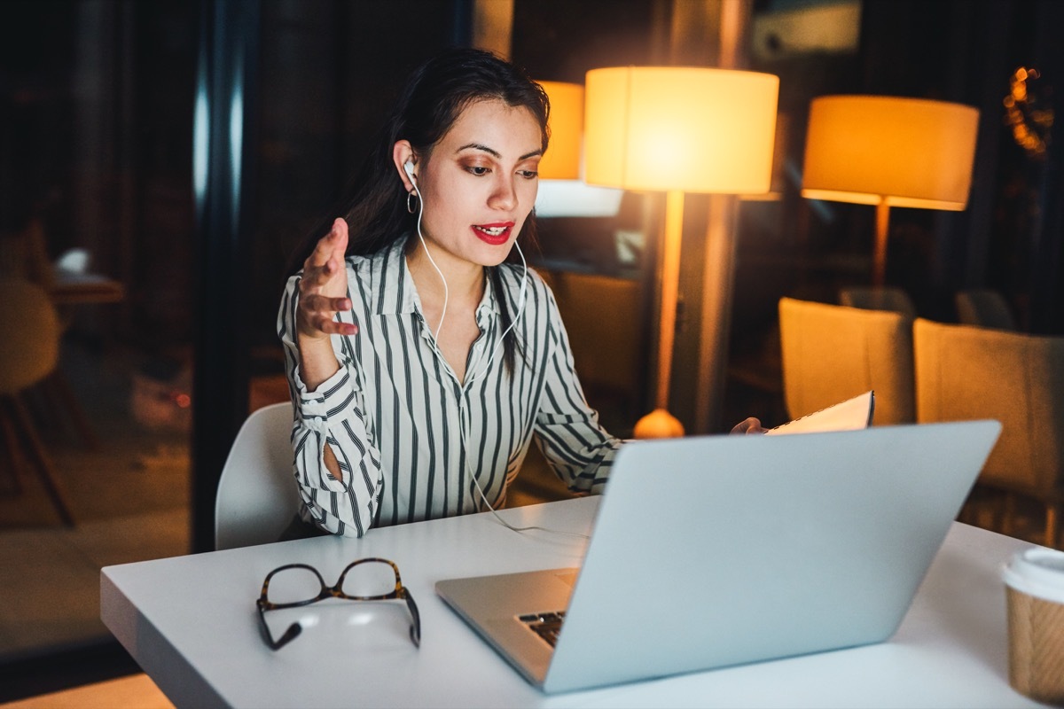 Shot of a young businesswoman using a laptop to make a conference call during a late night at work