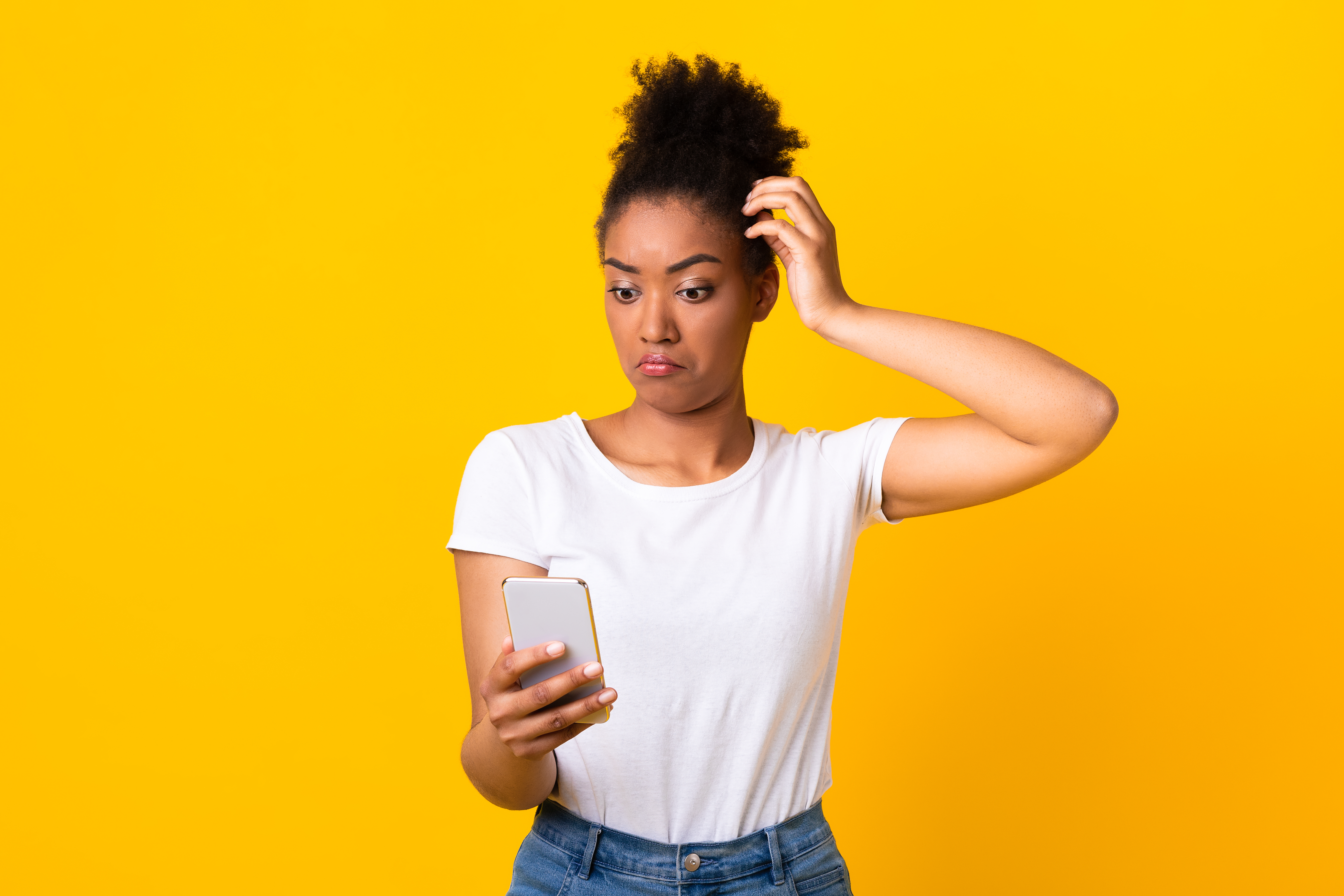 woman scratching her lead while looking at her phone