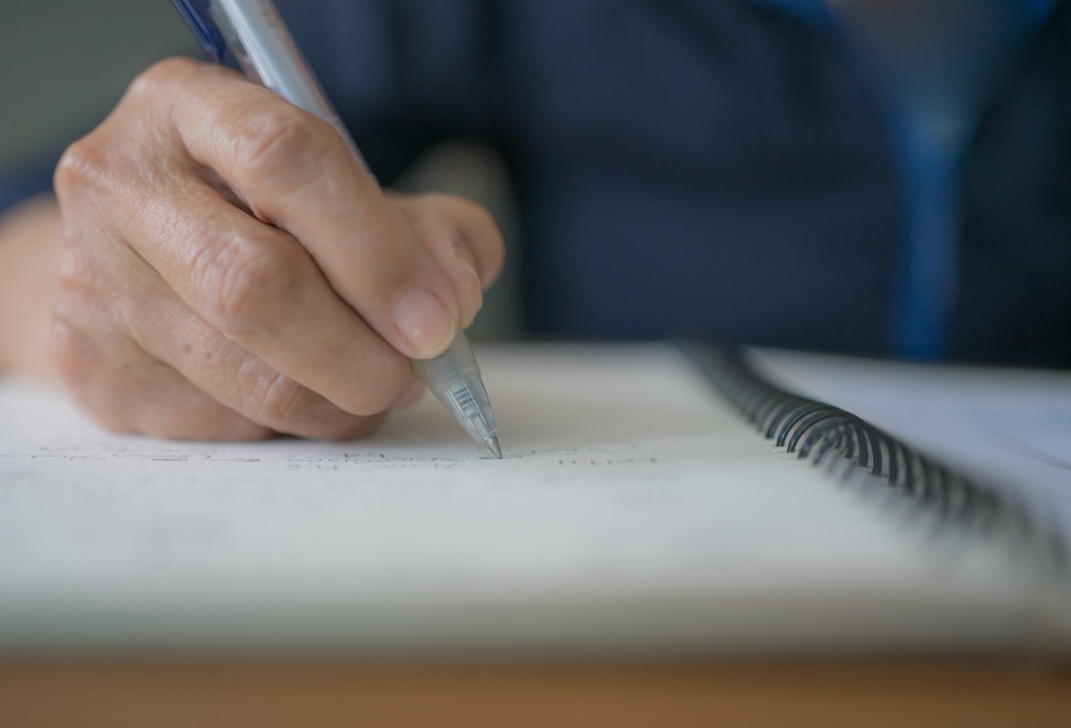 Closeup of a person's hand writing with a pen in a pad of paper