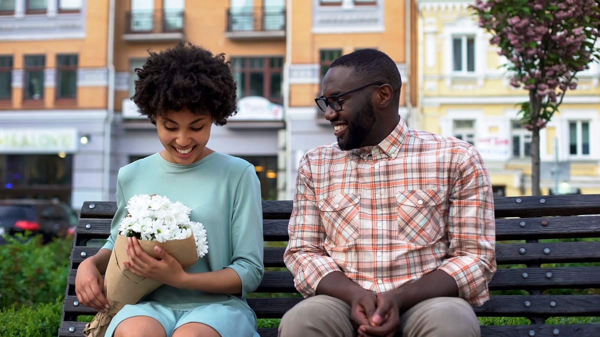 Woman holding flowers and man sitting on bench