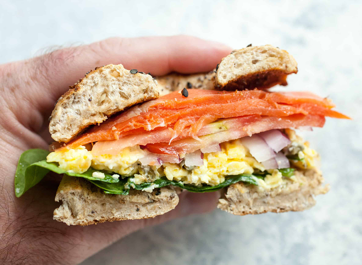 Lox breakfast bagel sandwich in hand cut in half