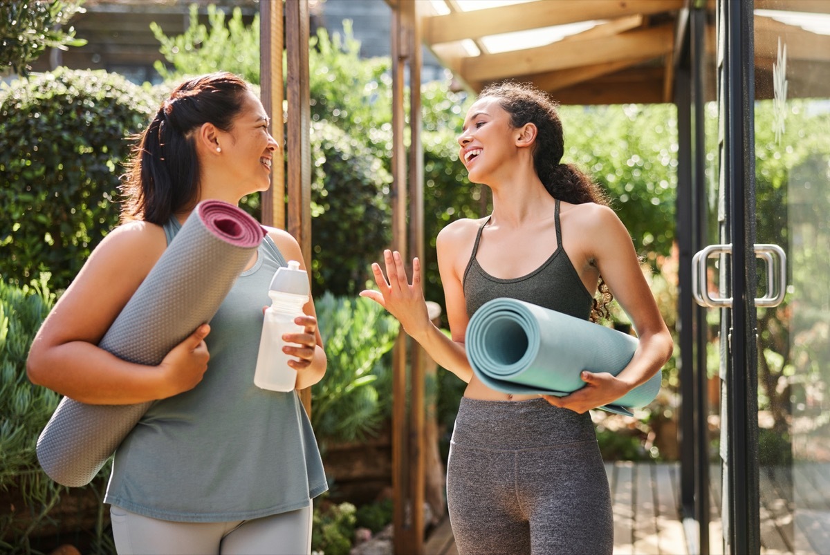 Two females walking out of a yoga class, talking and smiling