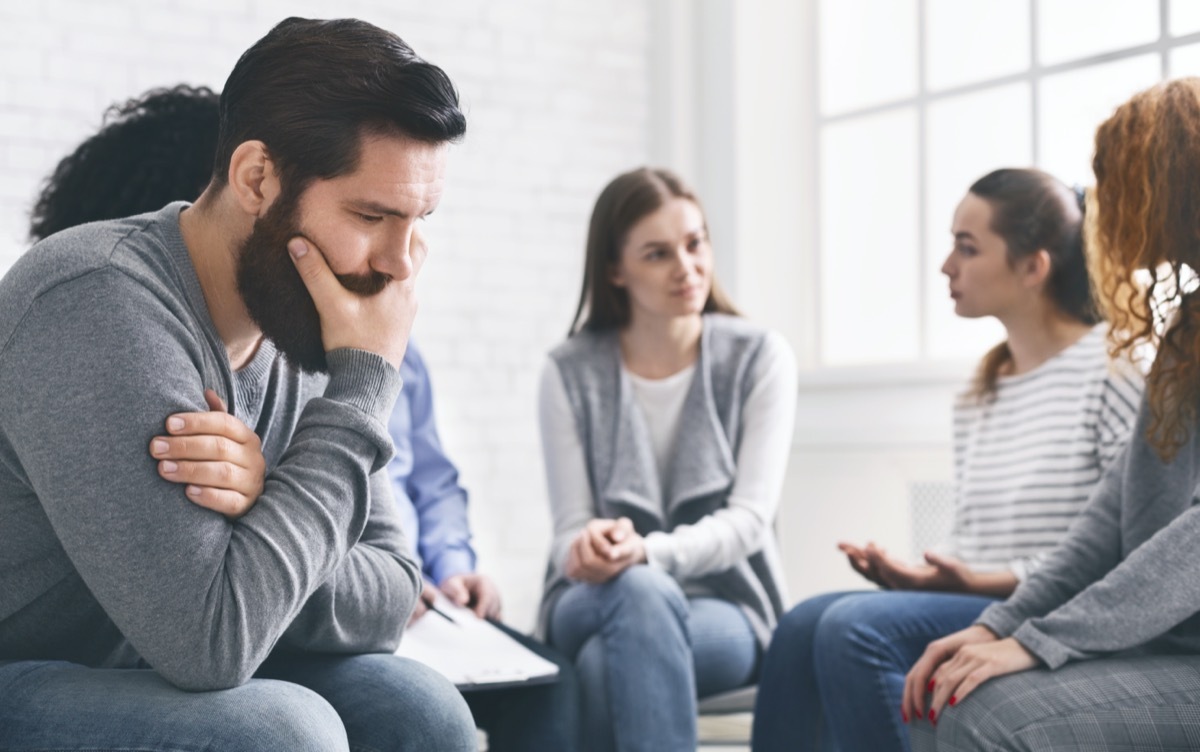 Psychotherapy, depression, life issues concept. Depressed man sitting at rehab group therapy and thinking about his problems