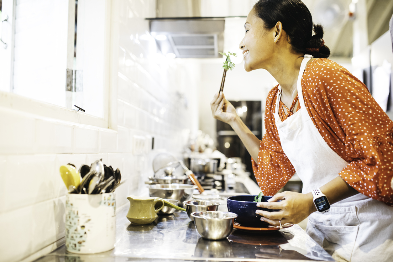 young woman tasting food from soup bowl