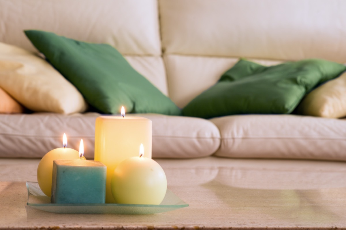 lit candles on a marble table and in the background a sofa with pillows, which