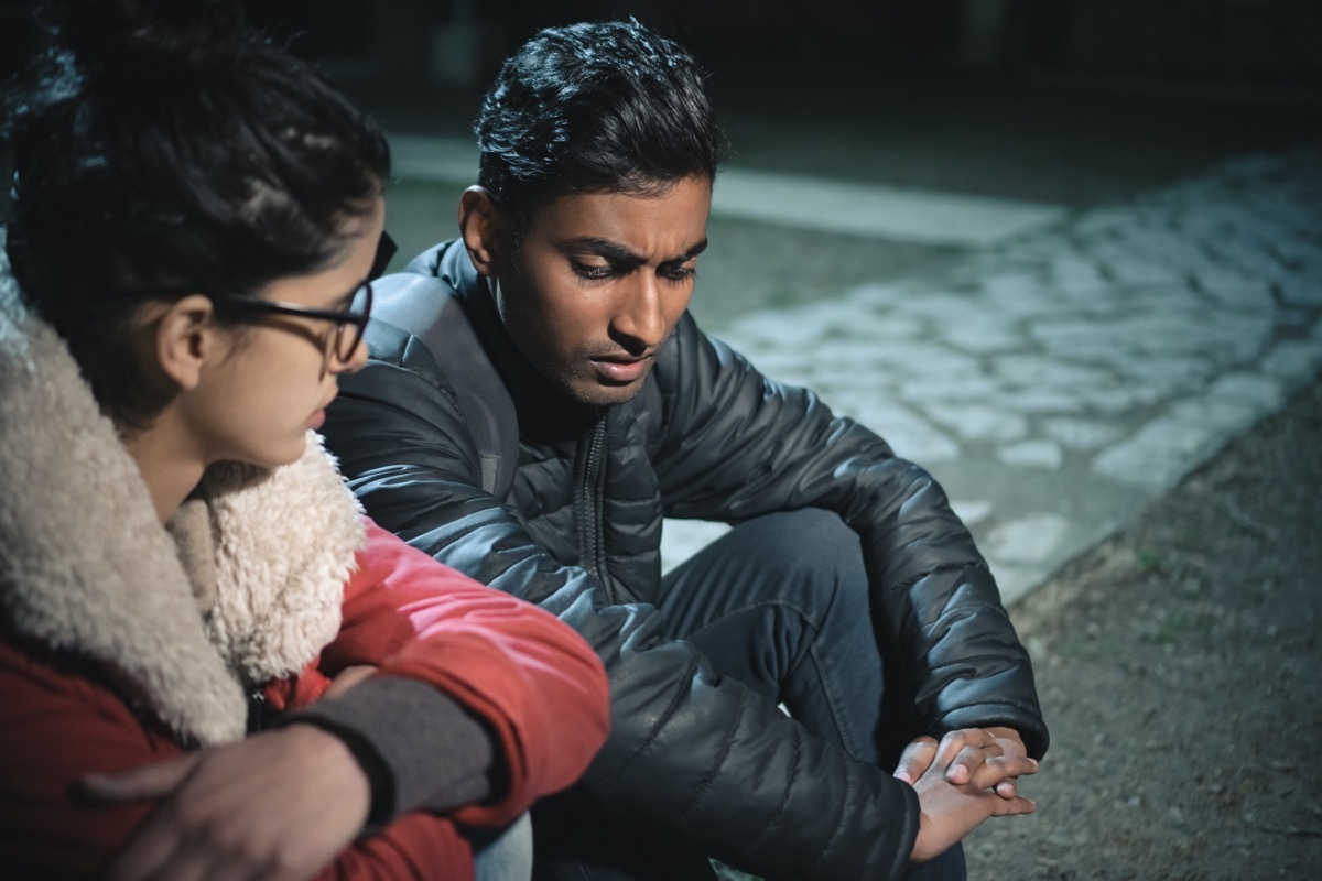 two serious people sitting in the park talking late at night