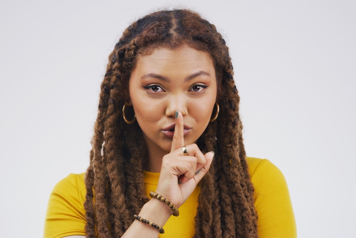 woman making shh sign with hand doing something sneaky