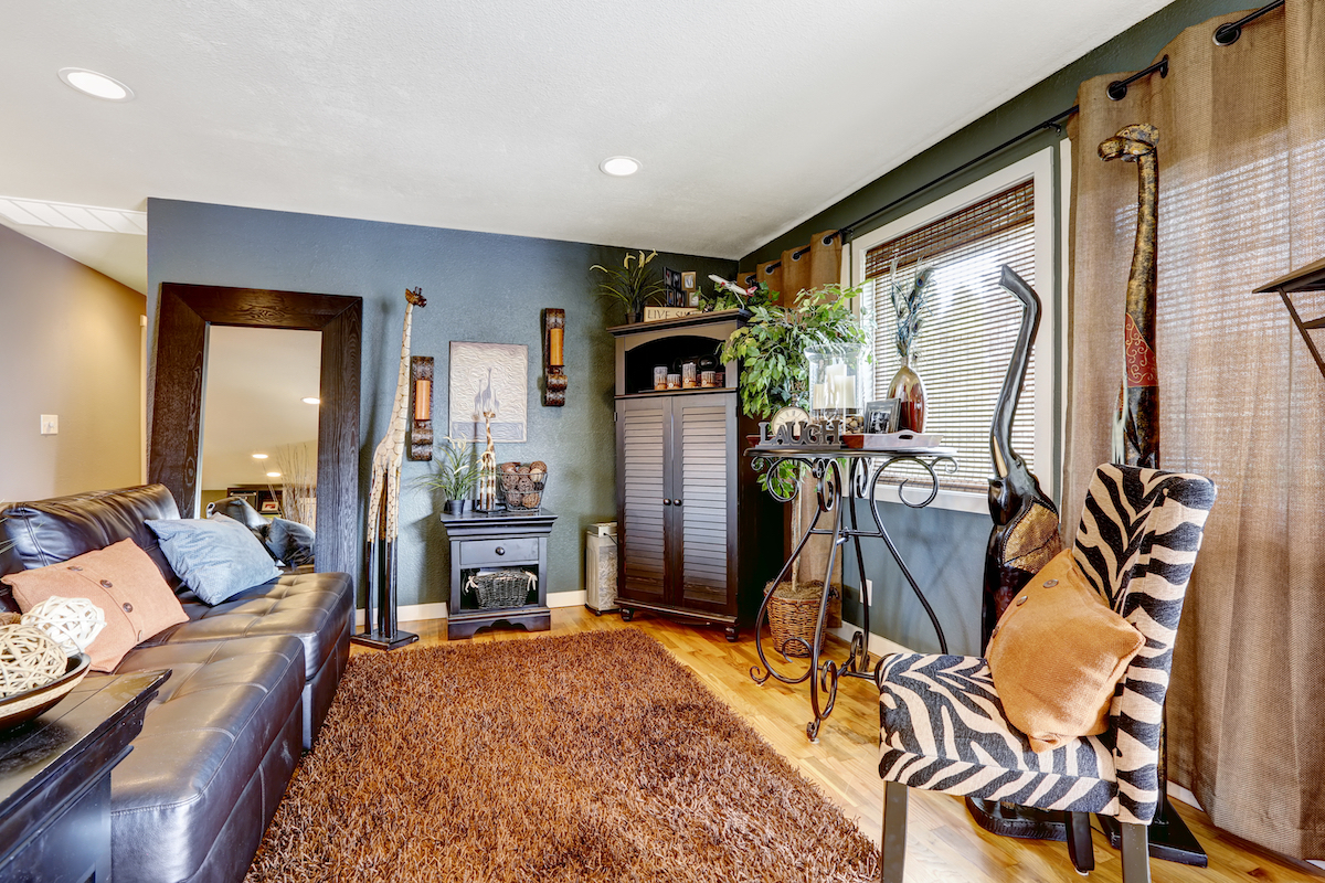 Tropical theme living room with exotic animal statues, brown soft rug, leather couch and zebra print chair