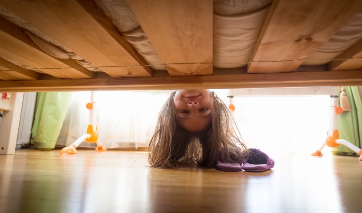 young girl looking under bed