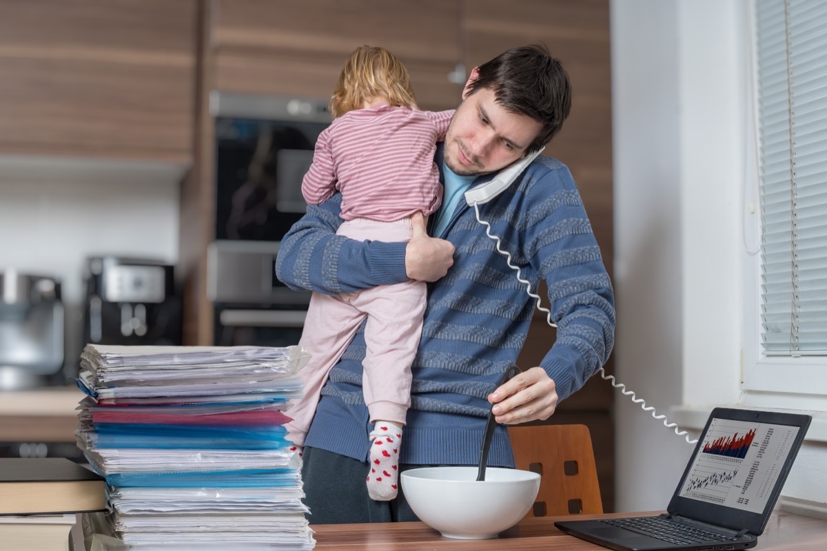 busy dad trying to work, carrying a baby