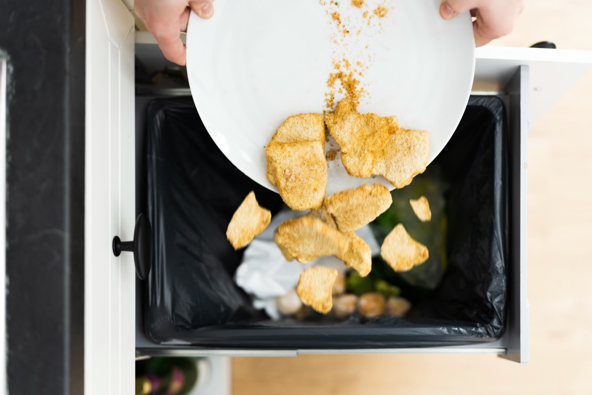 person throwing away cooked chicken nuggets