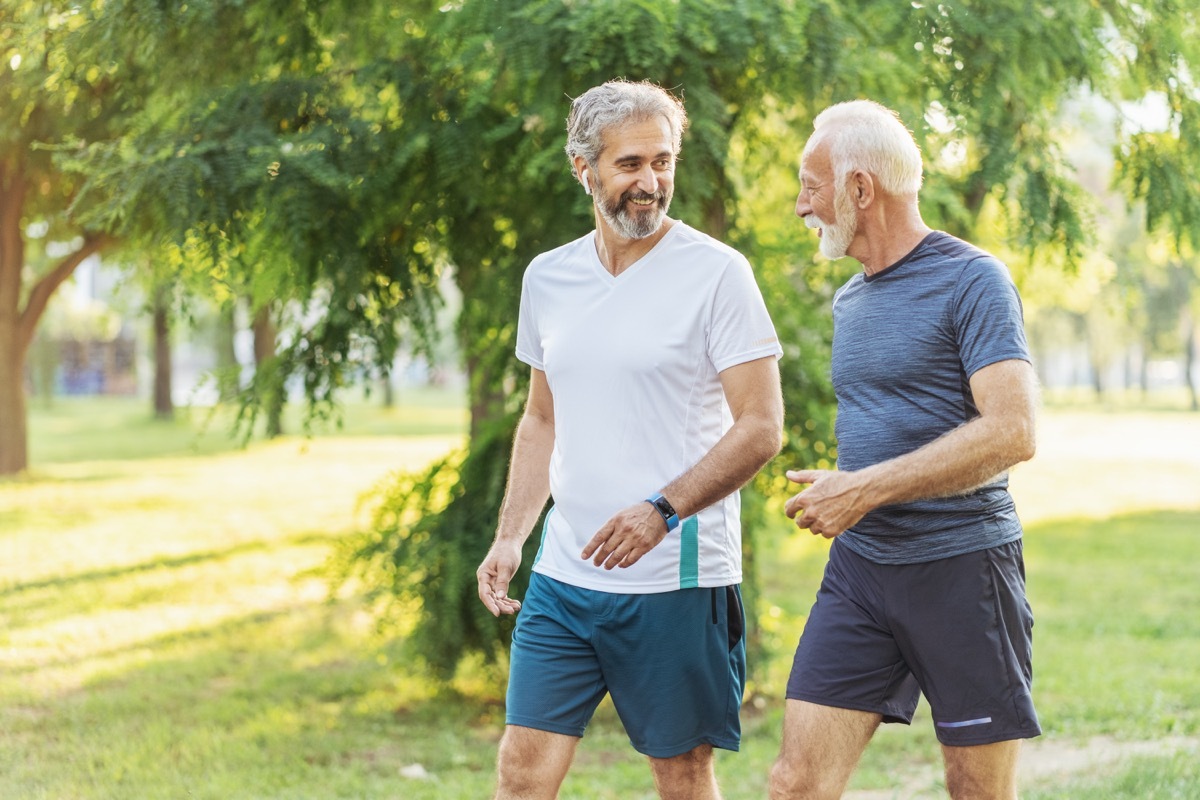 Two senior men walking and talking in a park