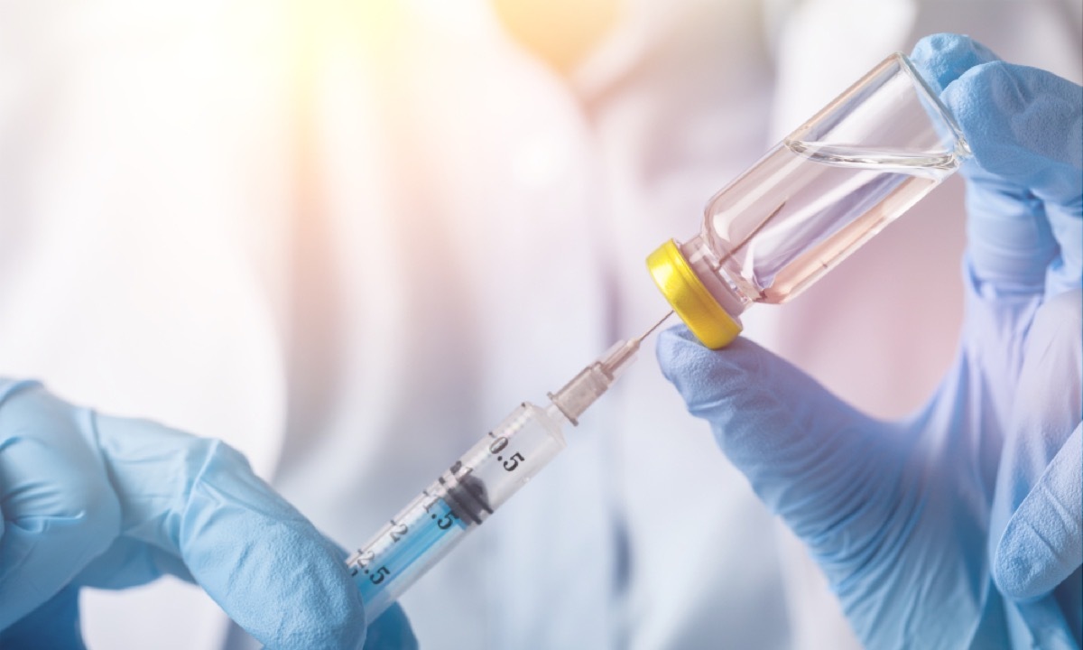 close up of doctor withdrawing vaccine with needle