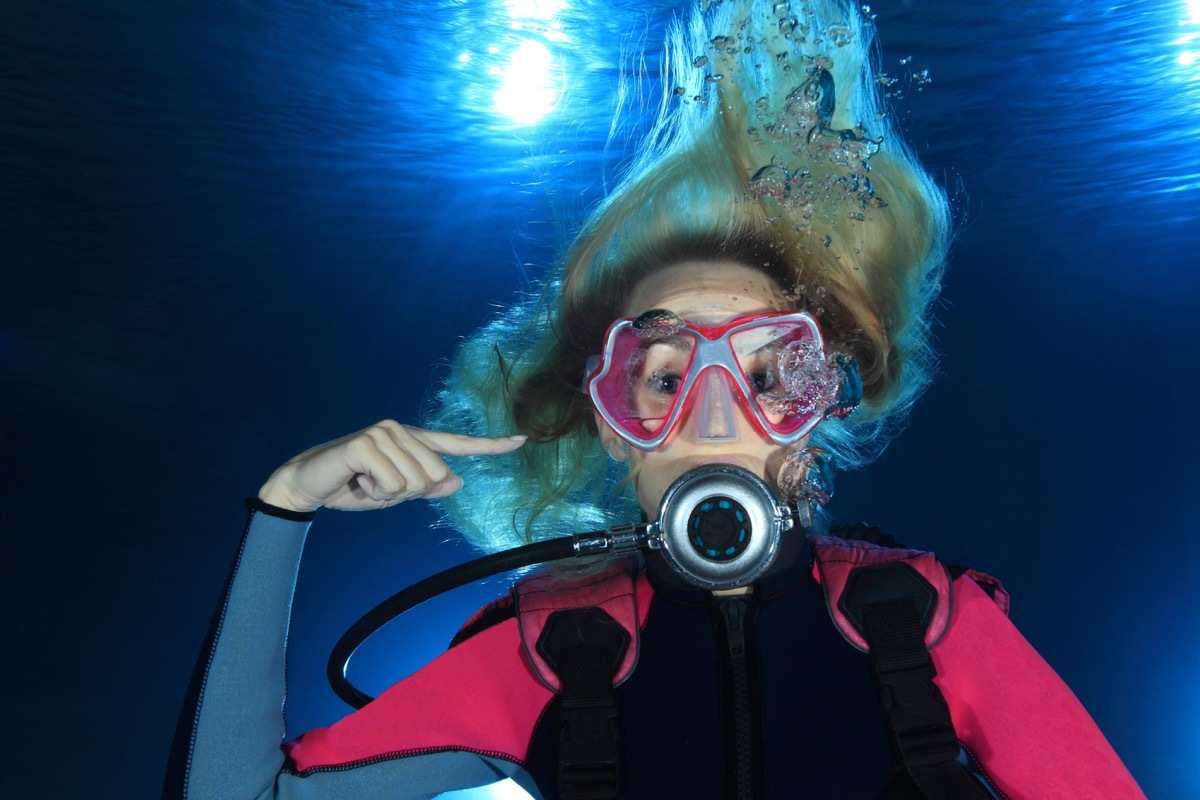 Female scuba diver show the underwater sign for ear problems