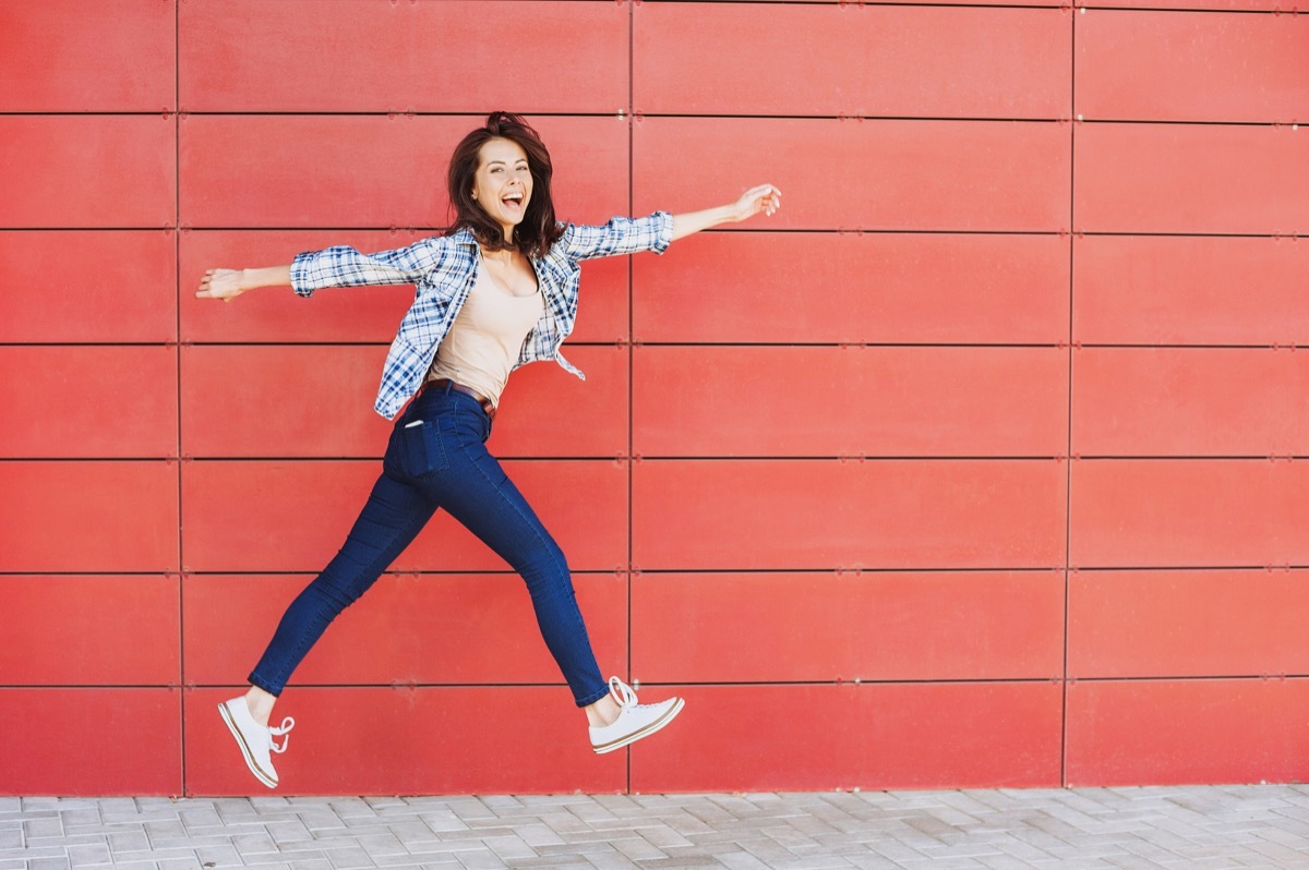 happy woman jumping against a a red wall