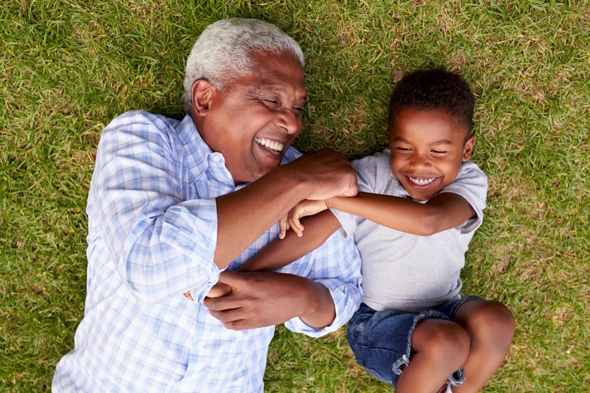 Black grandpa and grandson play in grass in yard, dangers lurking in backyard