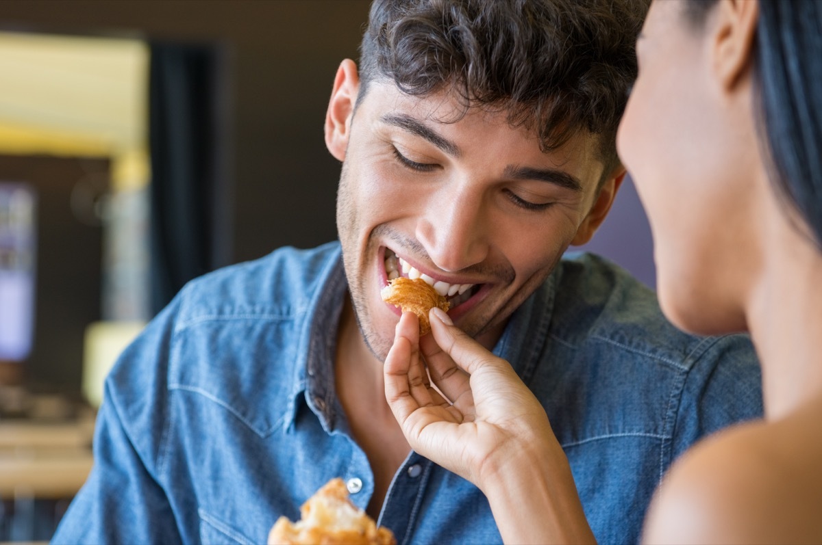 young woman feeding asian man some bread