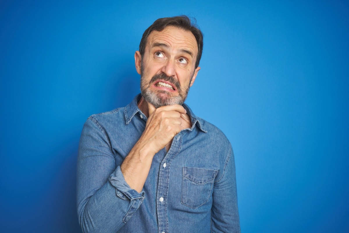 Middle age man with grey hair thinking, concerned and nervous with hand on chin