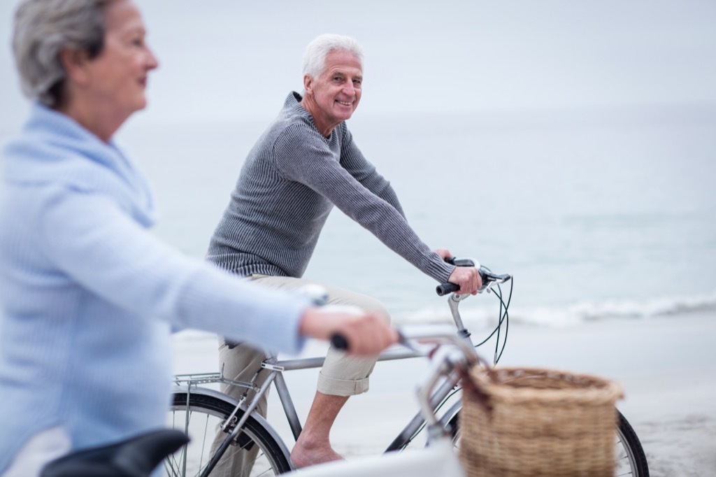 man and woman riding bikes on beach - how to dress over 50 