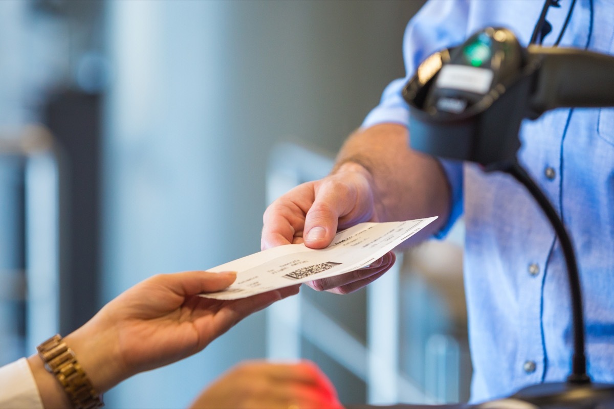 Airline attendant doing boarding for flight at airport, scanning ticket. Close up of hands, unrecognizable person.