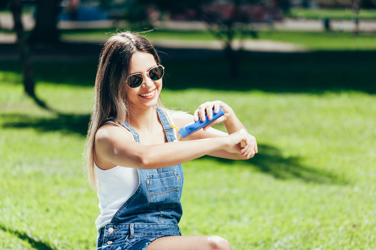 Girl putting on sunscreen in the park