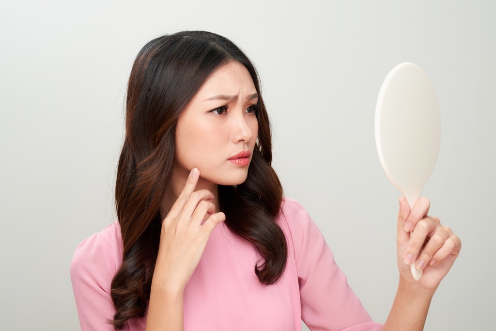 woman looking in handheld mirror