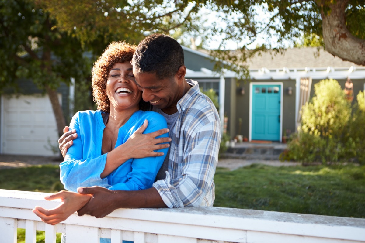 Middle aged couple hugging in their front yard