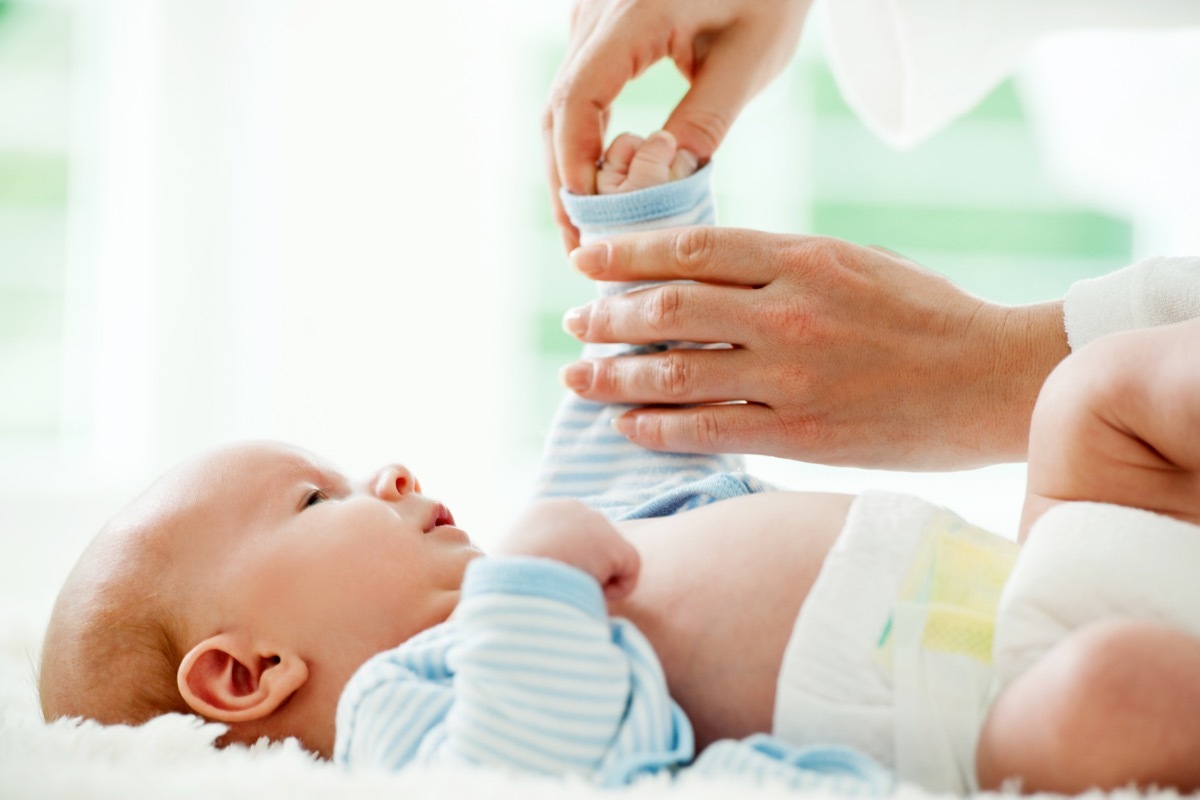 Mother dressing a cute baby boy. 