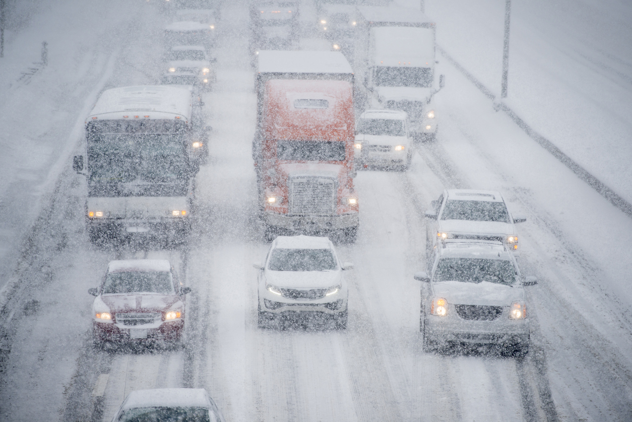 Trucks and cars driving down a highway in a snow storm