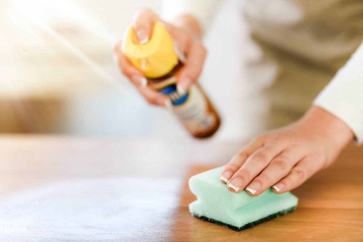 white hand cleaning wood with sponge