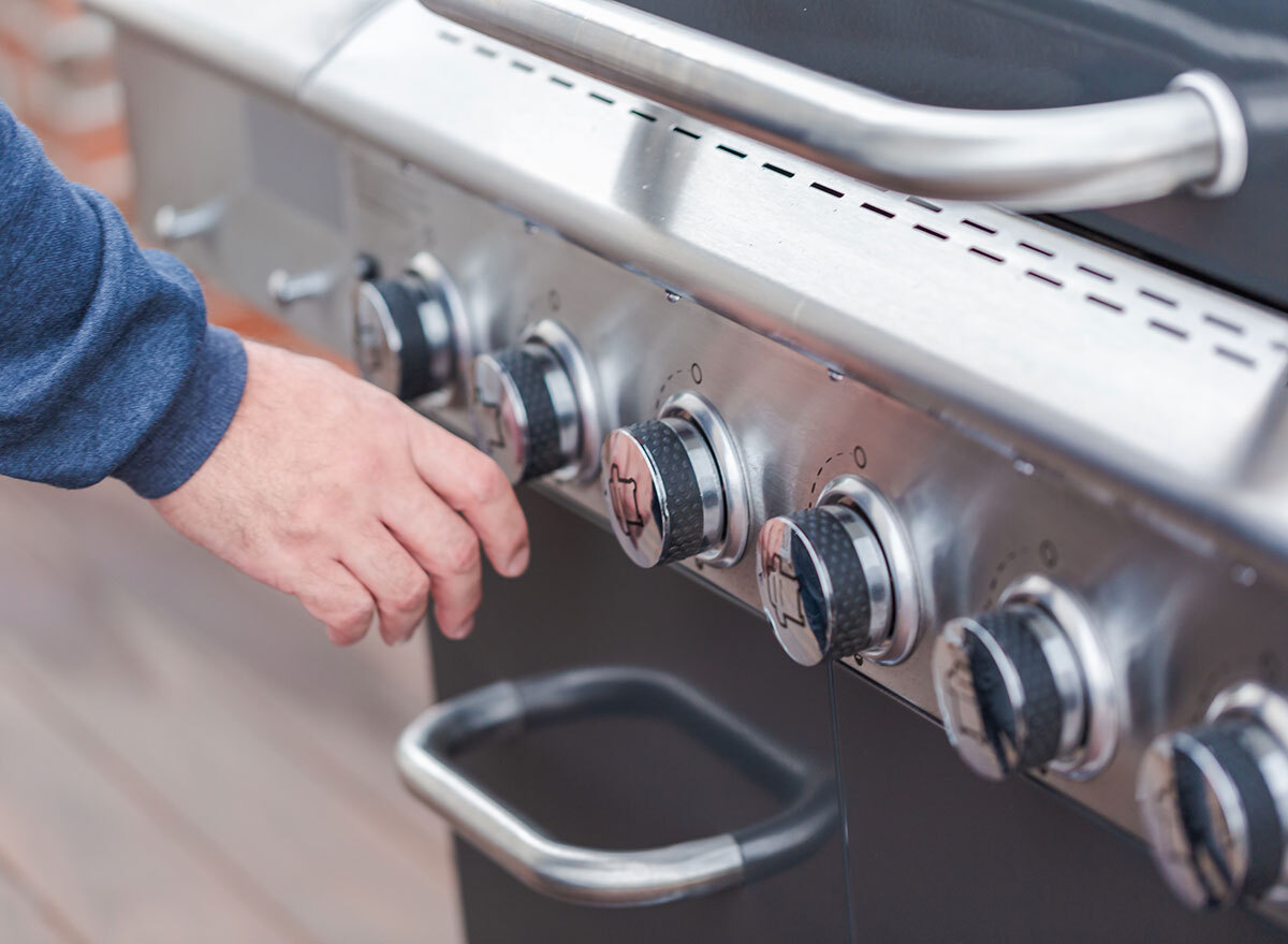 man touching grill knobs