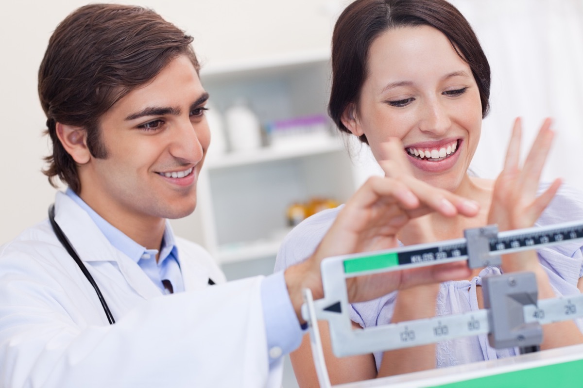 Young male doctor adjusting scale for excited patient