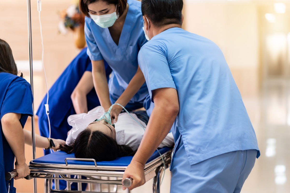 Medical team do CPR Cardiopulmonary resuscitation to seriously injured patient with oxygen mask while push gurney stretcher bed to Operating Room. Emergency health care and medical hospital concept.