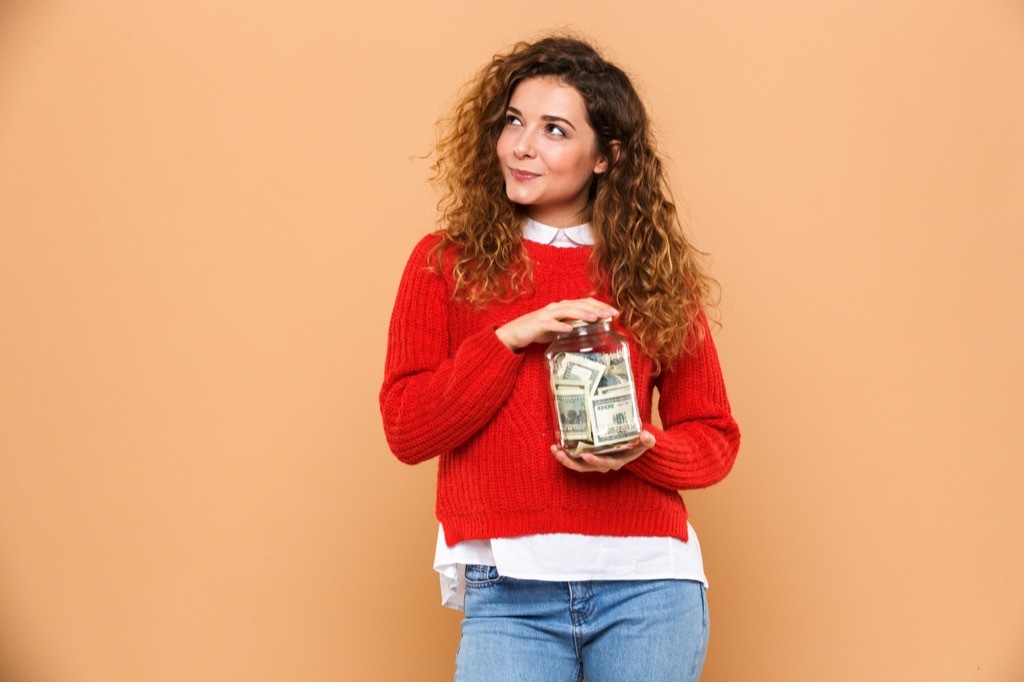 woman holds jar of money and wonders if it makes her an adult.