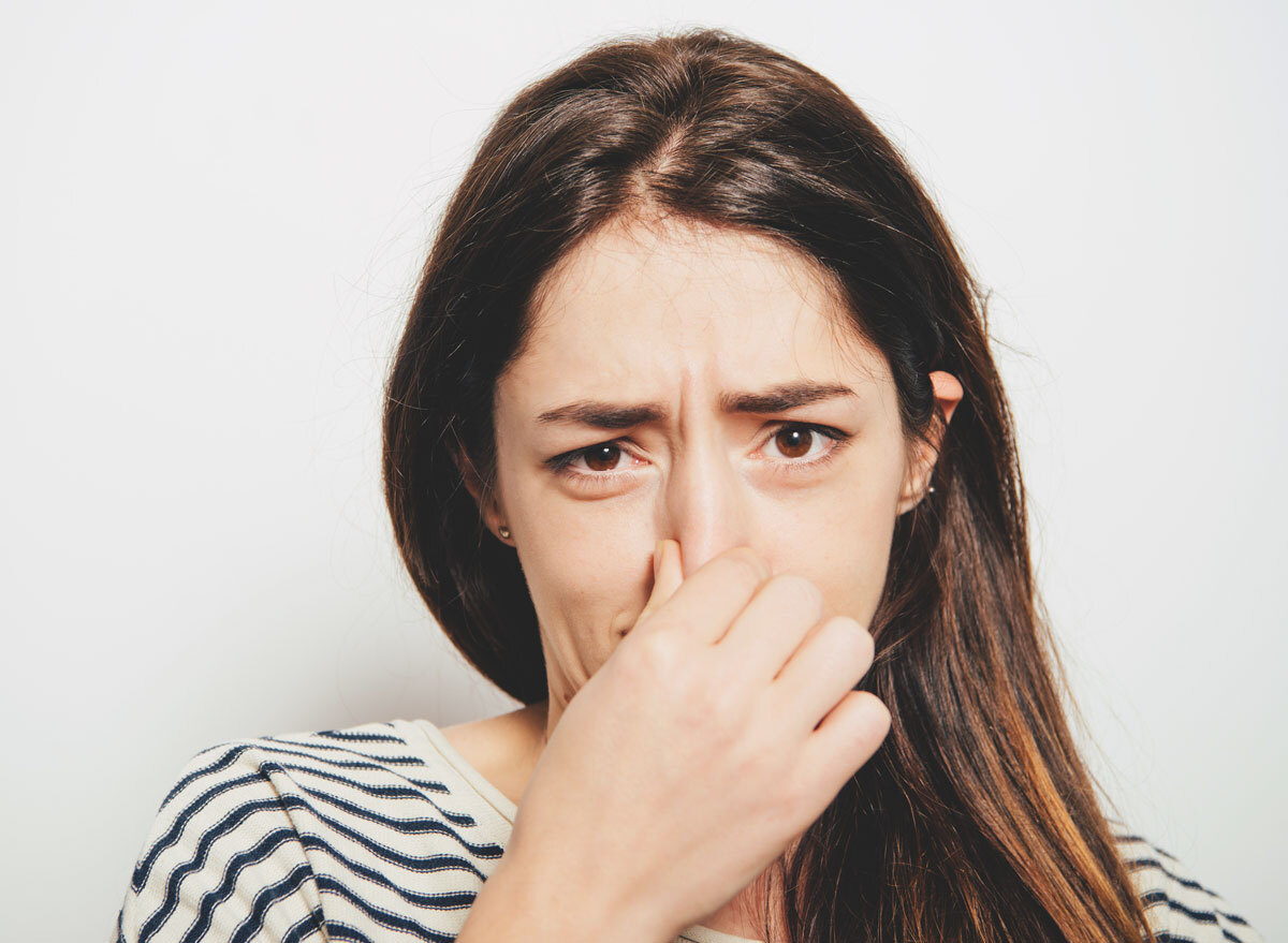 Woman holding nose because of bad smell